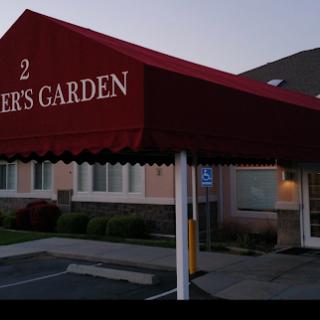 An evening view of a restaurant with a red awning, displaying its name prominently.