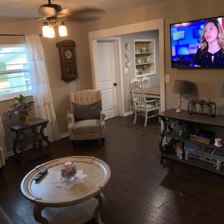 A cozy living room with modern decor, featuring a TV, armchair, coffee table, and hardwood flooring.