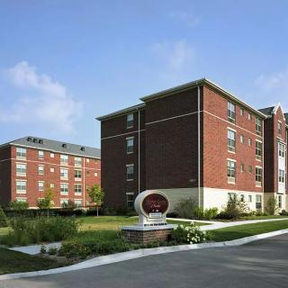 A multi-story brick residential building with landscaped surroundings on a clear day.