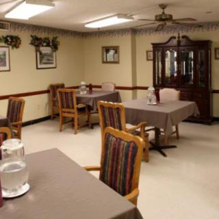 A dining room with multiple tables and chairs, featuring classic decor and soft lighting.