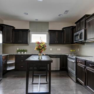 A modern kitchen interior with dark cabinetry and a central island featuring a flower arrangement.