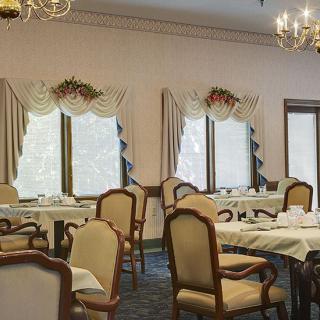 An elegant dining room with tables and chairs, adorned with chandeliers and curtains.