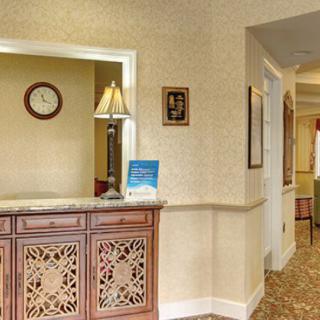 Reception area with a wooden desk, lamp, and visible hallway.