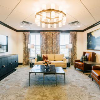 A stylishly decorated living room featuring a central chandelier, comfortable seating, and elegant decor.