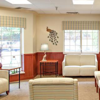 A cozy living room with sofas, large windows, and a decorative wall piece.