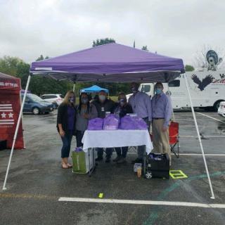 A team gathered under a purple tent at an outdoor event, ready to engage with the community.