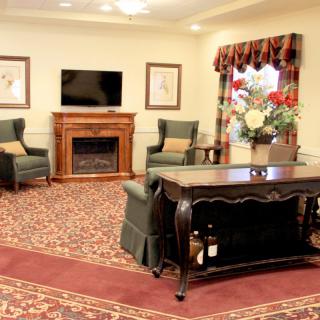A cozy living room featuring a fireplace, elegant furniture, and floral decorations.