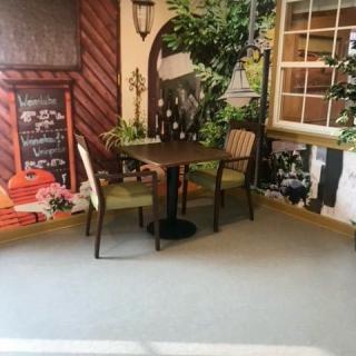 A cozy indoor cafe setting with a table and chairs surrounded by decorative plants and artwork on the walls.