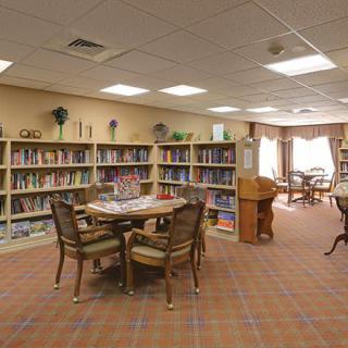 A cozy library room with bookshelves, a table, and chairs for reading.