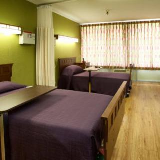 A hospital room with two beds, green walls, and curtains.