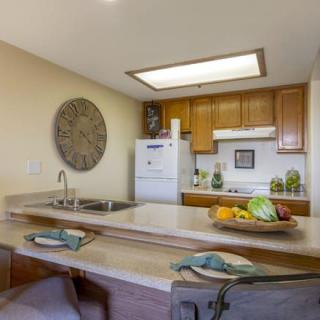 A cozy kitchen interior with wooden cabinets, a central countertop, and various kitchen appliances and decorations.