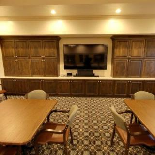 An elegant conference room with wood paneling, a large television, and seating for meetings.