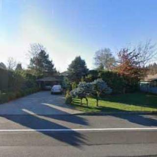 A residential house with a driveway and garden, featuring a car parked in front.