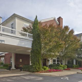 A well-maintained building entrance surrounded by greenery and trees.