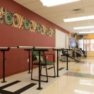 A rehabilitation gym with exercise equipment and parallel bars for physical therapy.