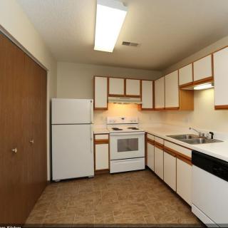 A small kitchen with white appliances and wooden cabinets.