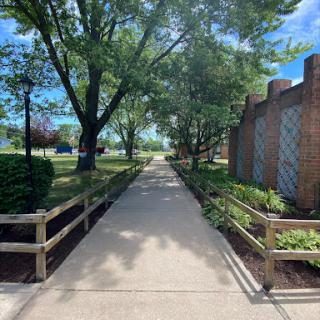 A serene walkway lined with trees and a wooden fence, inviting visitors to explore the peaceful surroundings.