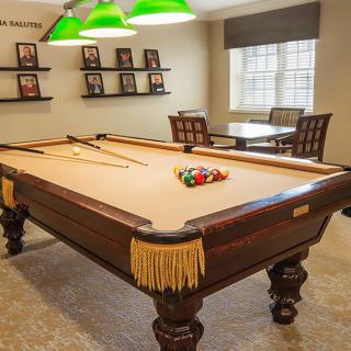 A cozy billiard room featuring a classic pool table with cue sticks and billiard balls neatly arranged.