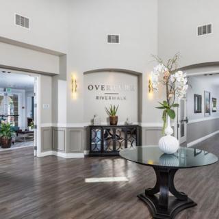 A modern lobby area featuring elegant decor, with a central table adorned with a vase and plants.
