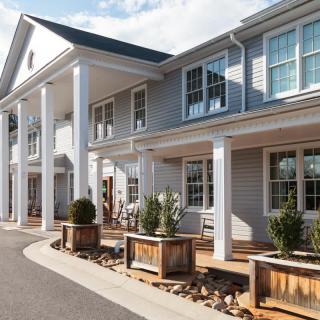 A modern residential building with white columns and a well-maintained exterior.