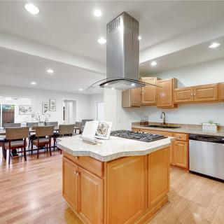 A modern kitchen with wooden cabinets, central island, and adjoining dining area.