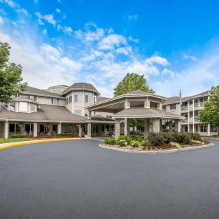 A large residential building with a circular driveway and landscaped entrance.