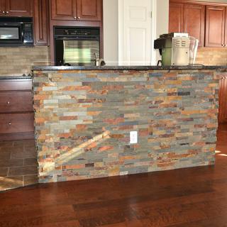 A kitchen with a stone veneer counter and hardwood flooring.
