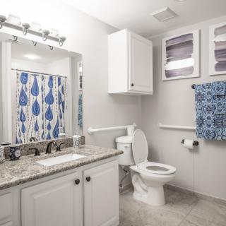 A modern bathroom with white cabinets and blue accents.