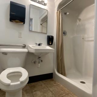A clean and simple bathroom with a shower, sink, toilet, and bathroom accessories.