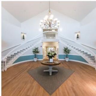 A grand and elegant lobby featuring a double staircase and a central chandelier.