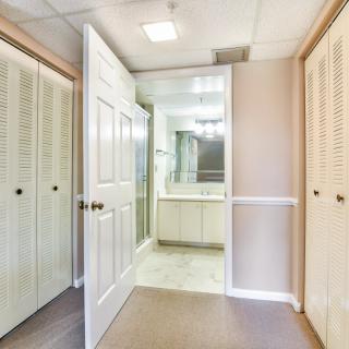 A hallway with wooden doors leading to a mirrored bathroom.