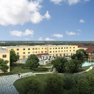A scenic view of a hotel surrounded by gardens and pathways under a clear blue sky.
