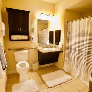 A neatly organized bathroom with warm lighting, featuring a toilet, sink, and shower area.