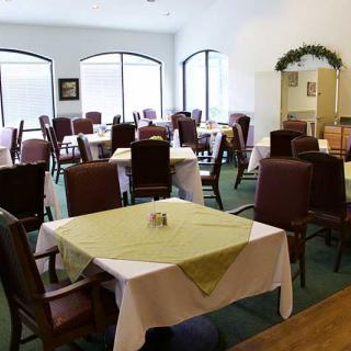 A dining area with tables and chairs arranged neatly, featuring tablecloths and decor.