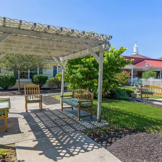 A peaceful garden with a pergola and outdoor seating.