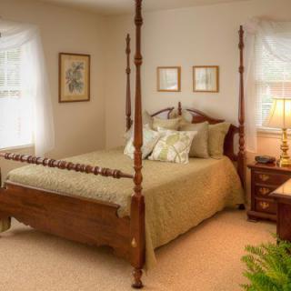 A cozy bedroom featuring a classic four-poster bed with elegant bedding, complemented by warm lighting and traditional decor.