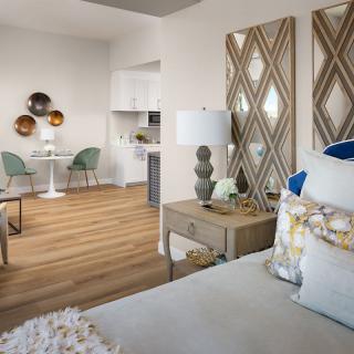 A modern living space featuring a cozy bedroom area with decorative wall art and a dining nook, illuminated by natural light.