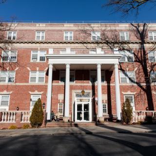 A historic brick building with white columns under a clear blue sky.