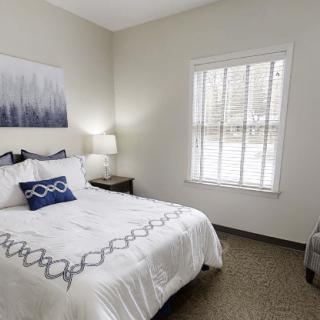 A cozy bedroom featuring a neatly made bed, tasteful decor, and a bright window.
