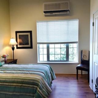 A cozy bedroom with a neatly made bed, window blinds, and soft lighting.