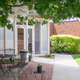 A peaceful outdoor patio with a table and chairs surrounded by greenery.
