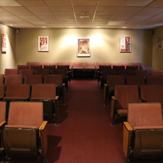 An empty theater with rows of seats and posters on the walls.