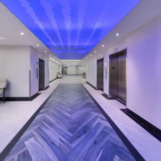 A modern hallway featuring elevators, stylish tile flooring, and a captivating blue ceiling.