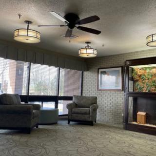 A cozy lounge area featuring comfortable chairs, a ceiling fan, and an aquarium.