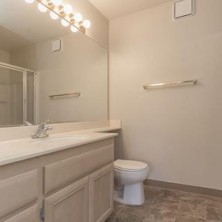 A clean and modern bathroom with a large mirror, vanity, and toilet.