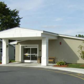 A small building with white columns and an entrance under a clear sky.