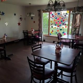 A cozy dining area with decorated windows and neatly arranged tables and chairs.
