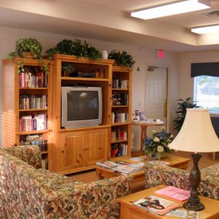 A cozy living room with a television set, bookshelves, and comfortable seating.