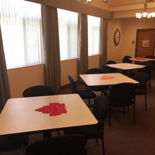 An empty meeting room with tables and chairs arranged in a well-lit space.