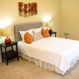 A well-decorated bedroom with a neatly made bed, side tables with lamps, and artwork on the wall.